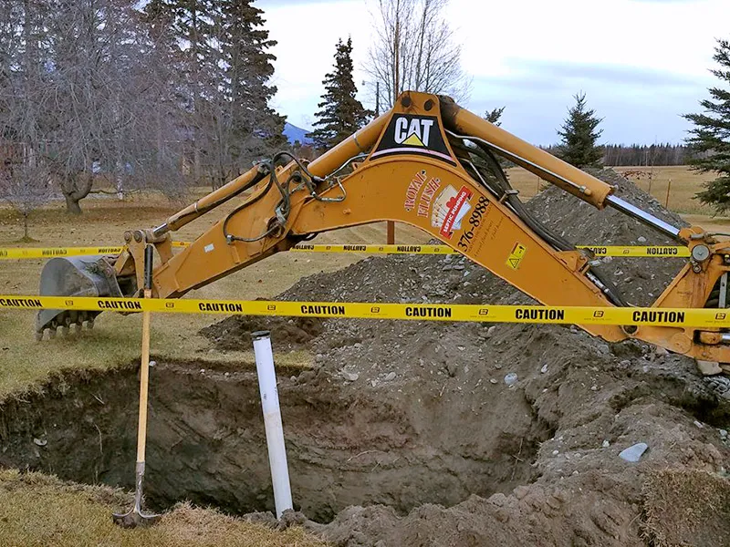A Royal Flush branded excavator digs a hole for the installation of a new septic tank.
